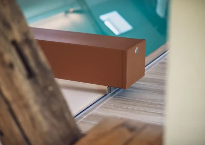 Een structuur van bruin hout en metaal is bevestigd aan de rand van een turquoise binnenzwembad met een lichte houten vloer.