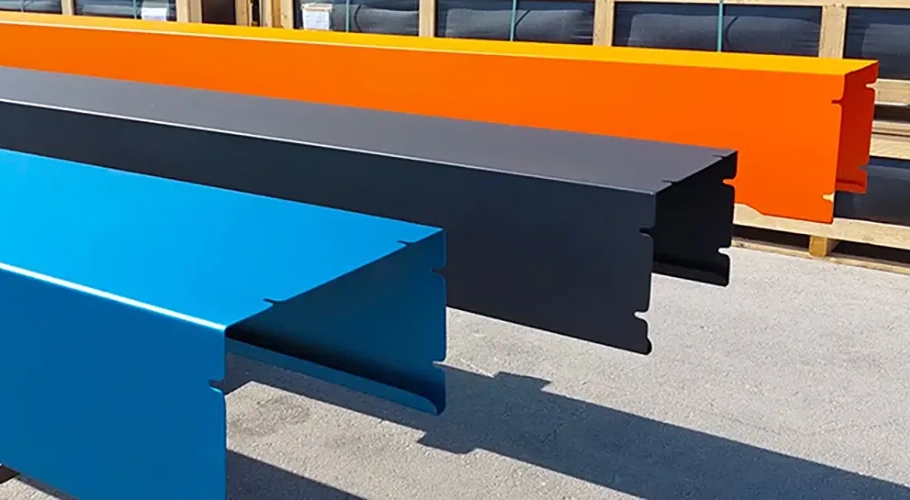Trois profilés métalliques colorés, en bleu, noir et orange, sont alignés horizontalement sur une surface grise.