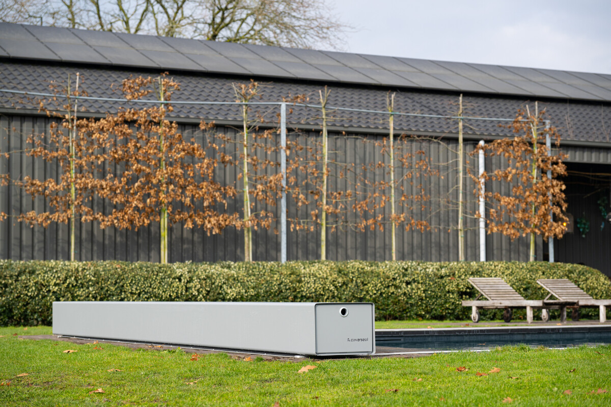 Vue aérienne d’une maison en pierre avec piscine équipée d’une couverture Coverseal grise, intégrée harmonieusement dans la terrasse en pierre claire.