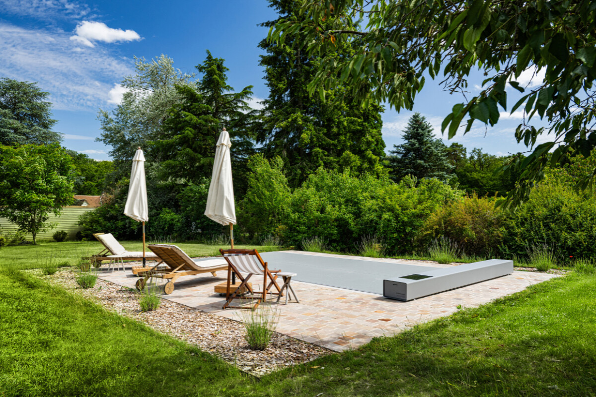 Vue aérienne d’une maison en pierre avec piscine équipée d’une couverture Coverseal grise, intégrée harmonieusement dans la terrasse en pierre claire.